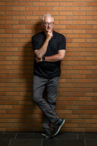 David Cordova posing in front of a brick wall in Paccar Hall.