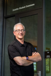 David Cordova, who recently retired from Deloitte, standing in front of the Deloitte Student Commons.