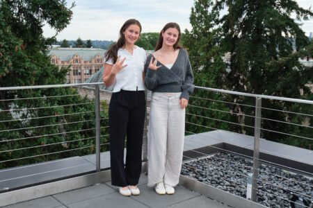 Amanda and Hana Moll making the "Dubs Up!" sign on the patio of Founders Hall